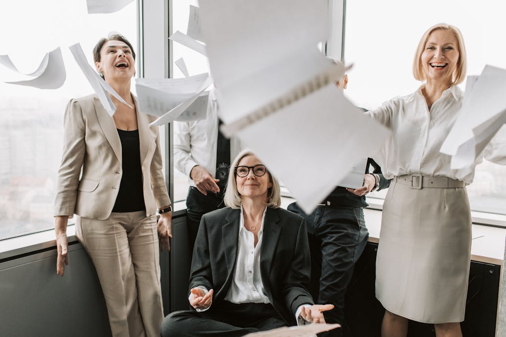 A joyful group of business colleagues celebrates success in a modern office setting.